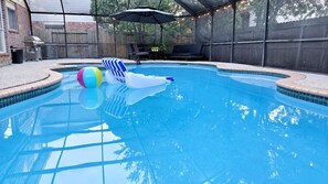 Una piscina con zona cubierta, sillas de descanso y una parrilla para barbacoa.