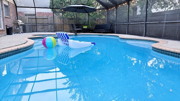 Piscina com área coberta, espreguiçadeiras e churrasqueira.