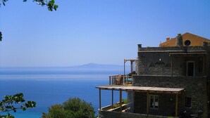 A stone building with a balcony overlooking a body of water and distant mountains. - Aegean Castle Suites Greek Hospitality Experience (Andros)