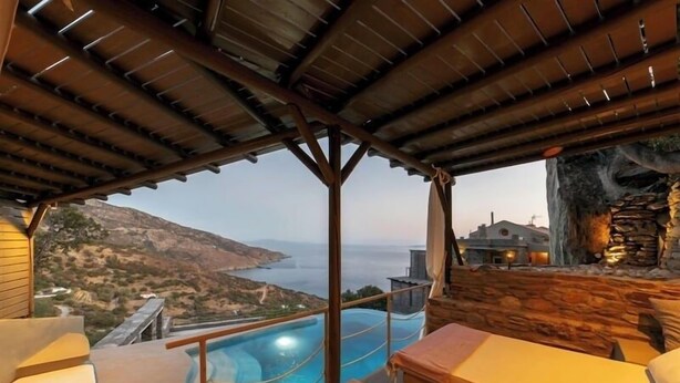 A poolside area with a view of the sea and hills. - Aegean Castle Suites Greek Hospitality Experience (Andros)