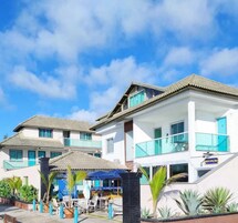 Un hotel con varias construcciones, mesas al aire libre y cielo despejado.