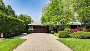 A residential driveway leading to a garage, surrounded by well-maintained hedges and trees. - Stunning Lake View 3BR Home with Serene Japanese Garden & Pond (Lake View)