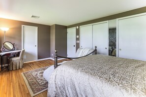 Quarto com cama, escrivaninha com cadeira, espelho e guarda-roupa.