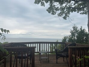 A wooden deck with outdoor furniture, overlooking a body of water. - Your Lakefront Escape: 3BR Retreat with Japanese Garden and Sunset View (Lake View)
