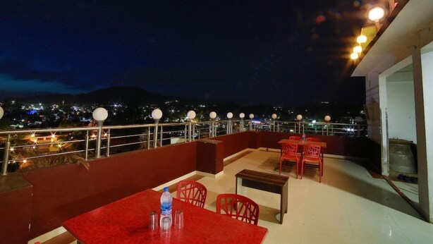 Una terrazza esterna con tavoli e sedie, una bottiglia d'acqua e vista sulla città illuminata di notte.