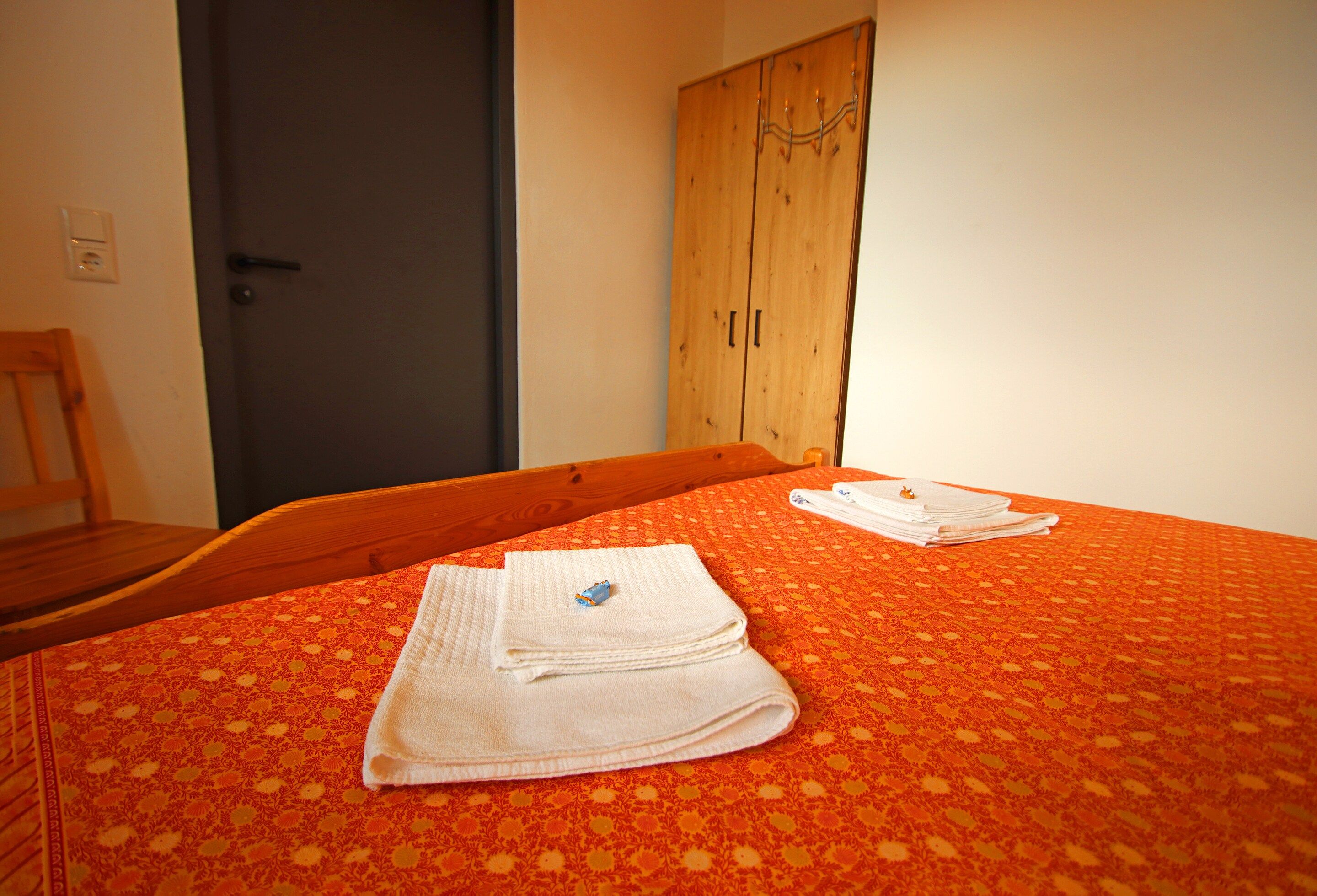 Una habitación con cama, armario de madera y una puerta.