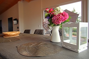 Ein Esstisch mit Blumen in einer Vase, Untersetzern und einem weißen Laternenlicht.