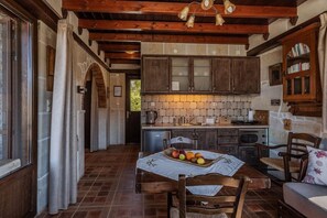 Une cuisine rustique avec des meubles en bois, un pare-feu en carreaux et un coin repas avec une table mise pour deux personnes.