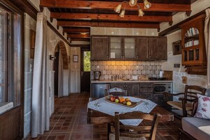 Una cocina rústica con armarios de madera, salpicadero de azulejos y un rincón comedor con una mesa preparada para dos personas.