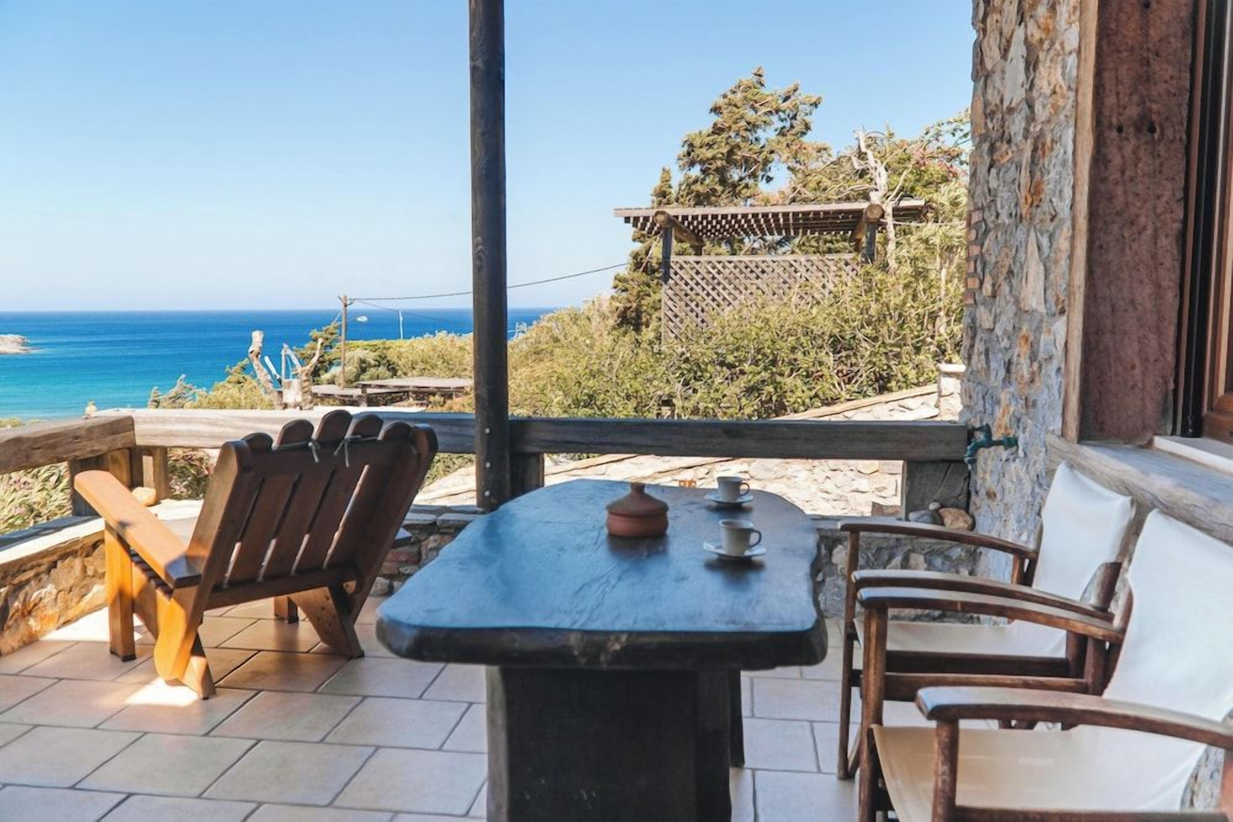 An outdoor seating area with a table and chairs, overlooking a coastal view.