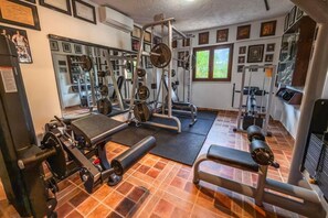 Ein Fitnessstudio mit unterschiedlichen Trainingsgeräten, darunter Kraftmaschinen und Kurzhanteln, sowie einem Spiegel an der Wand.