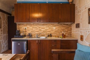 Eine kleine Küche mit Holzschränken, einer eingebauten Spüle und einem kleinen Kühlschrank.