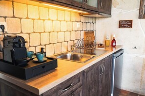 Eine Küche mit Steinrückwand, einer Kaffeemaschine, einem Spülbecken und einem Geschirrgestell.
