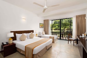A hotel room with two beds, a desk, a chair, a phone, and a painting on the wall. - South Lake Resort (Koggala)