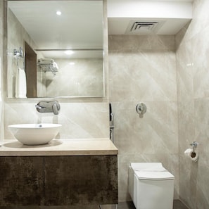 A modern bathroom with a large mirror, a white sink, a shower, and a toilet. - OYO Premium Paltan Bazar (Guwahati)