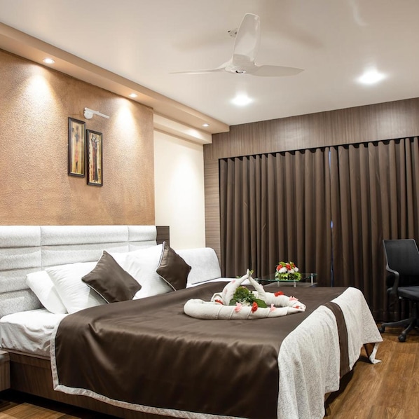 A modern hotel room with a large bed, a desk, and a chair. - OYO Premium Paltan Bazar (Guwahati)