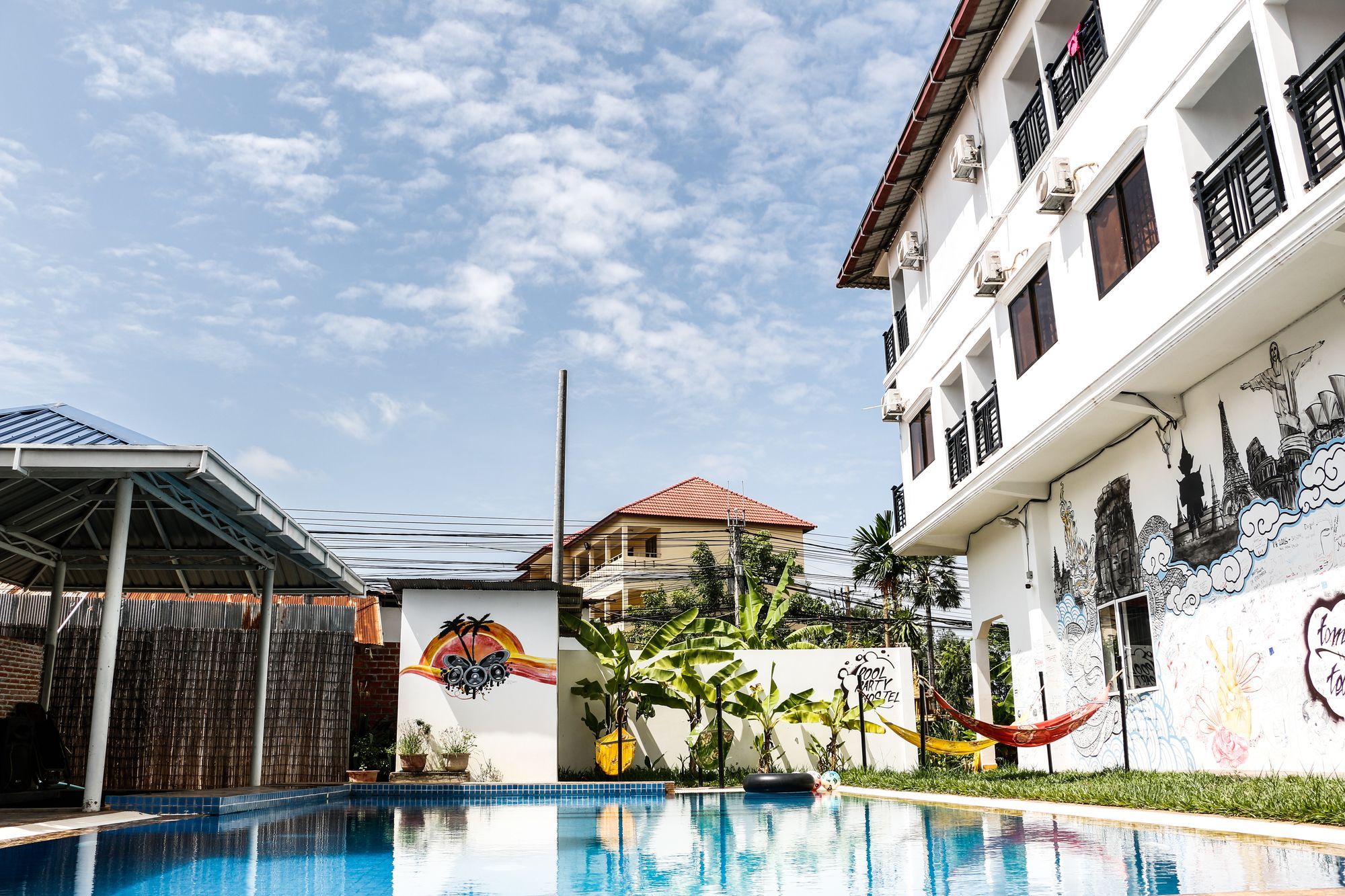 A swimming pool with a mural, a covered area, and a building with balconies.