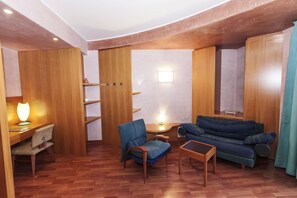 A compact living space with a sofa, chairs, a small table, and a lamp. - Terme Orvieto Hotel (Abano Terme)