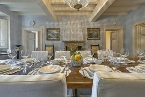 Un comedor formal con una larga mesa dispuesta para una comida, flanqueada por sillas, y una chimenea al fondo.