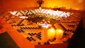 A hot tub with mosaic tiles and two lit candles.