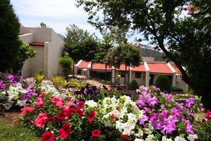 Un edificio con techo de tejas rojas y un jardín con flores coloridas.