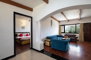 Une chambre d’hôtel moderne avec un lit, un canapé bleu, une petite table et une fenêtre avec des rideaux.