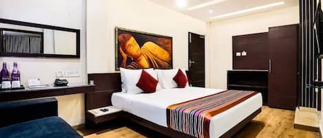 Una habitación de hotel moderna con una cama grande, un escritorio con computadora, una silla y un cuadro grande en la pared.