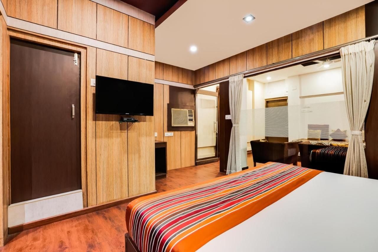 A hotel room with a bed, a television, a wardrobe, and a shower area.