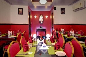 Un'area pranzo con tavoli apparecchiati per diversi ospiti, ognuno con tovaglioli e posate rosse.