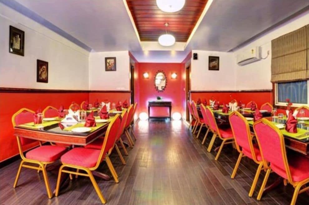 A restaurant with multiple tables and chairs, a central counter, and a red and white color scheme.