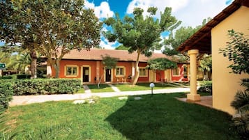 Ein Haus mit rotem Dach, ein Garten mit Rasen und Baum, und ein Weg, der zum Eingang führt.