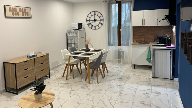 A modern kitchen with a dining area, a clock, and a microwave. - Elegant and cozy; apparently recently renovated (Béziers)