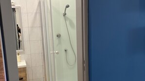 A bathroom with a glass-enclosed shower, white tiled walls, and a blue accent wall. - Elegant and cozy; apparently recently renovated (Béziers)