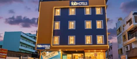 A multi-story hotel with a sign reading 'fabHOTELS' and a visible entrance with steps leading up to the door.