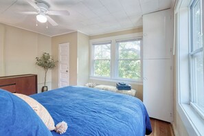 Ein Schlafzimmer mit einem Bett, einem Deckenventilator, einem Fenster und einer Tür.