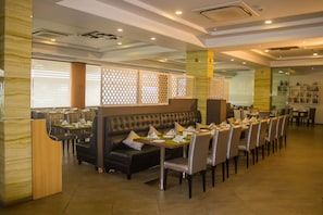 A restaurant with a long dining table, cushioned seating, and a decorative partition.
