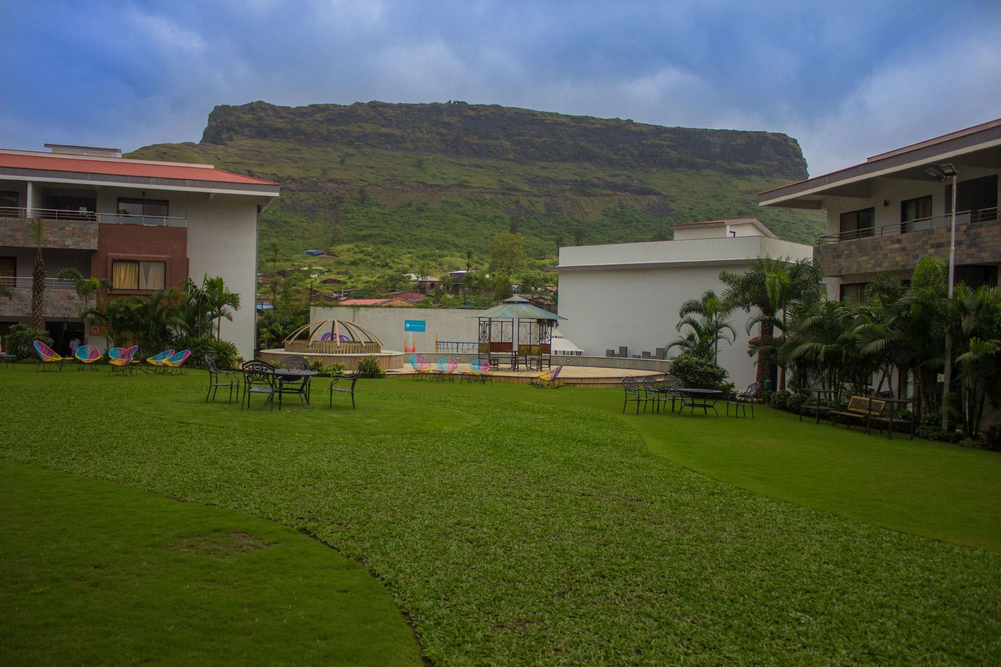 A courtyard with a view of a mountain, outdoor seating, and a gazebo.