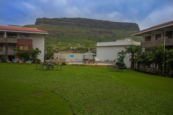 A courtyard with a view of a mountain, outdoor seating, and a gazebo.