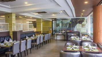 Un ristorante con diverse aree pranzo, tra cui postazioni a cabina e tavoli, caratterizzato da un design interno moderno e vista sull'esterno.