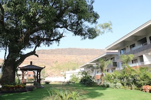A hotel with a large tree, a gazebo, and a view of a mountain.