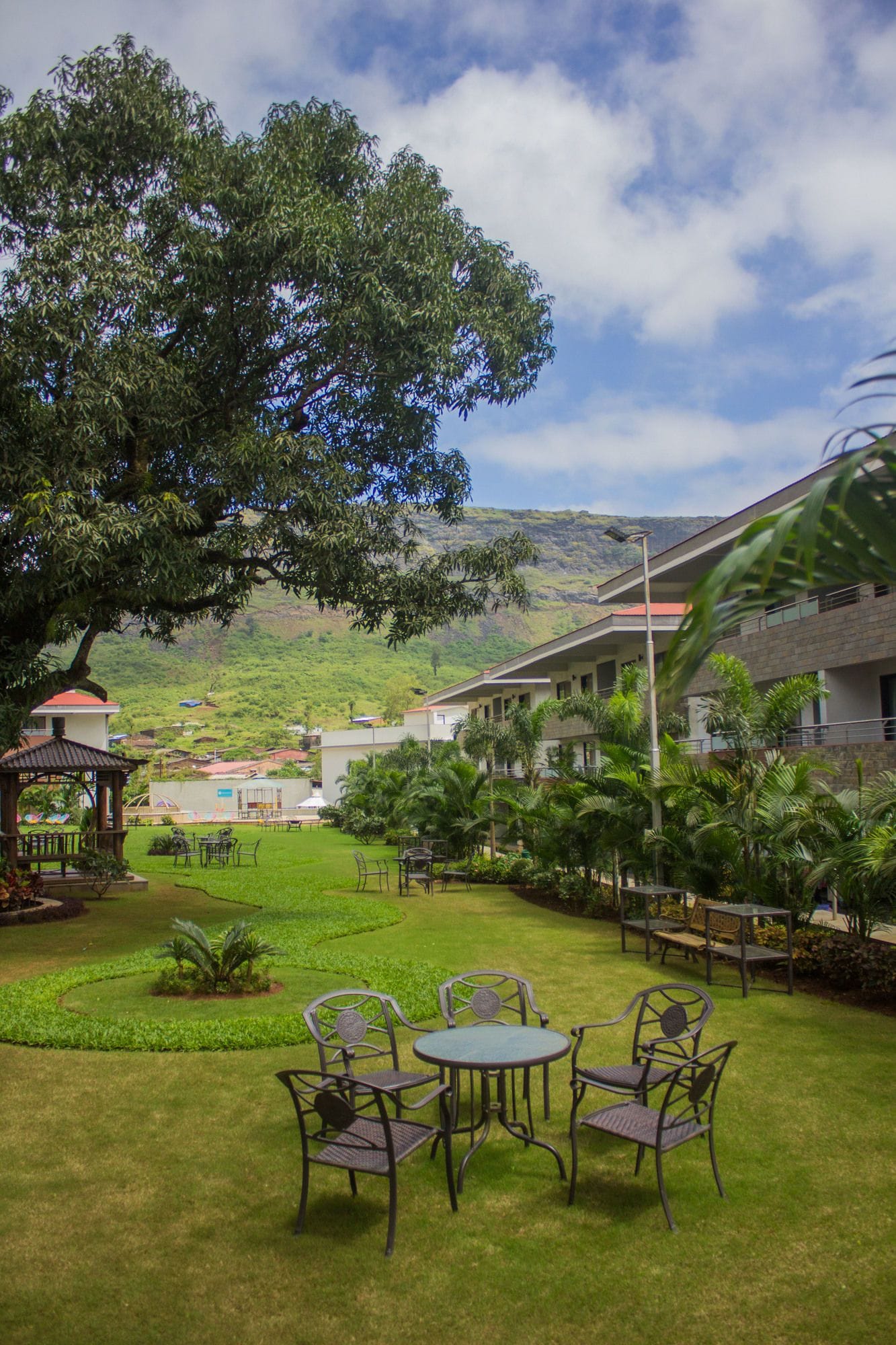 A hotel courtyard with a dining area, a gazebo, and a view of the surrounding hills.
