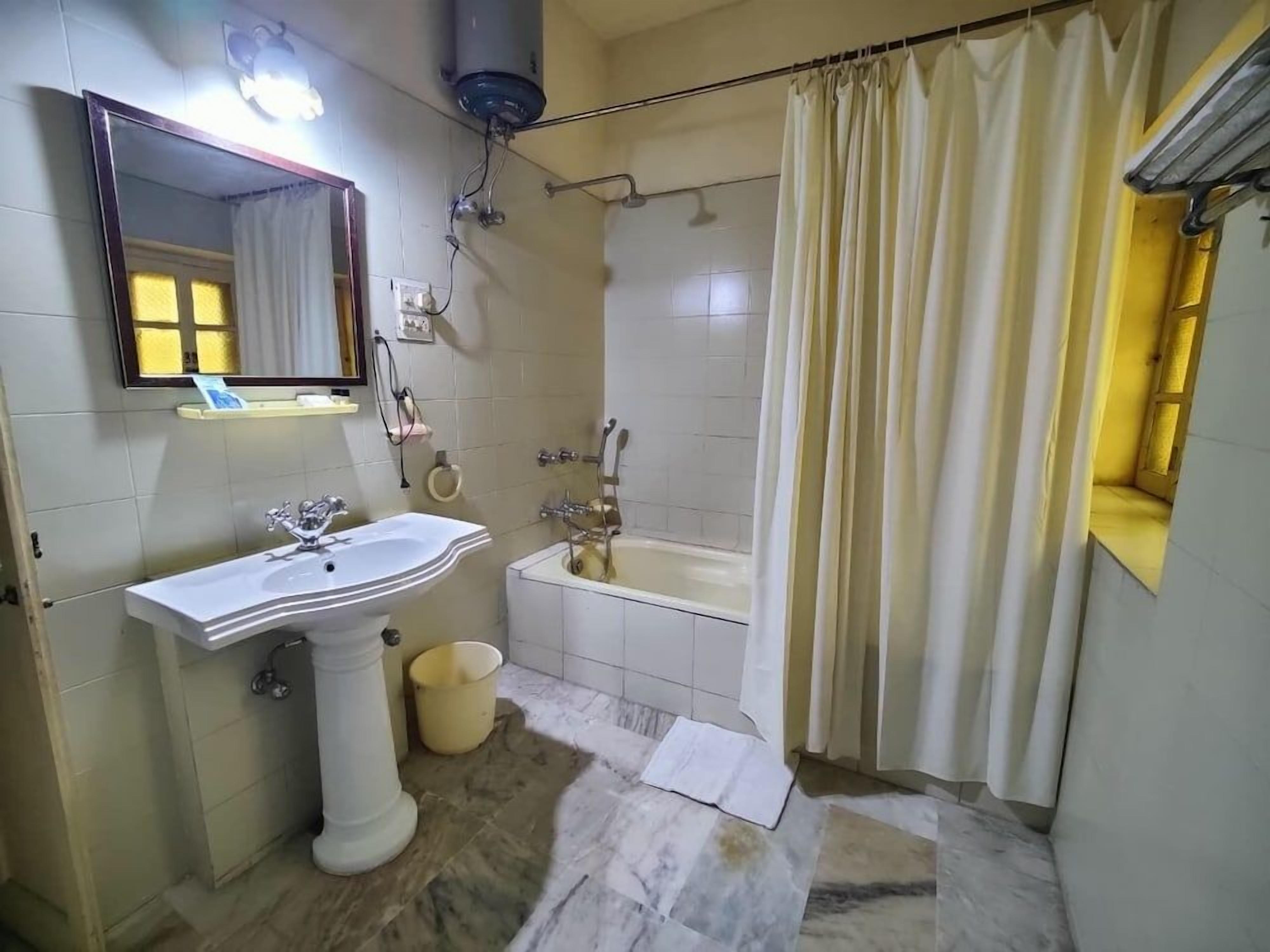 A bathroom with a pedestal sink, a bathtub, and a shower curtain.
