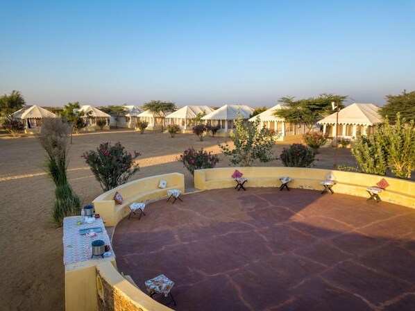 A desert resort with multiple tents and a central seating area with tables and chairs. - Wind Desert Camp (Jaisalmer)