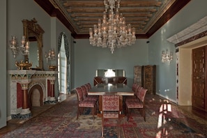 Un comedor formal con candelabro, chimenea decorada y mobiliario tradicional.