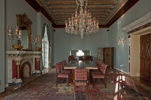 Un comedor formal con candelabro, chimenea decorada y mobiliario tradicional.