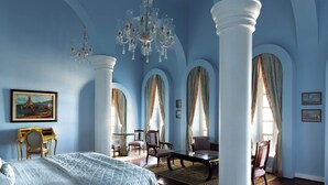 Une pièce spacieuse avec un grand lit, un lustre et un coin repas comprenant des chaises et une table.