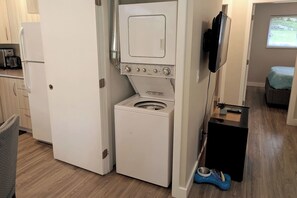 Cocina compacta con lavadora y secadora integradas, microondas y un pequeño comedor.