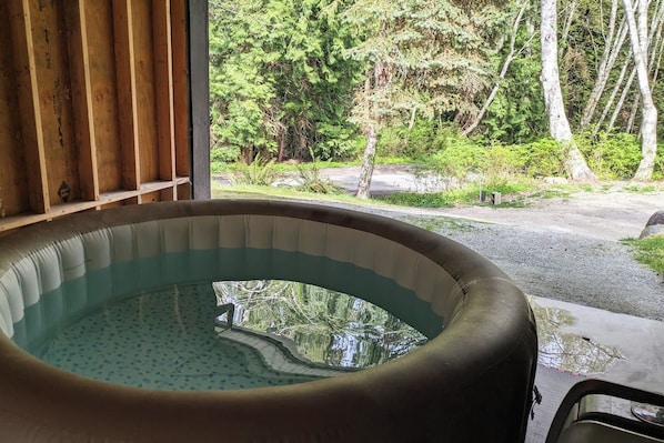 A hot tub with a view of a forested area.