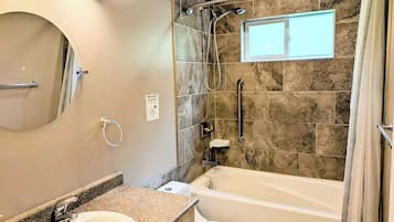 Une salle de bain avec une baignoire, une douche, un lavabo et un miroir.
