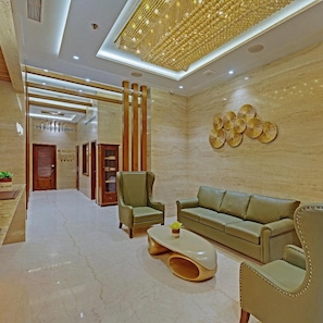 A modern interior with a sofa, chairs, a coffee table, and decorative wall art. - Treebo Metropolis (Mumbai)